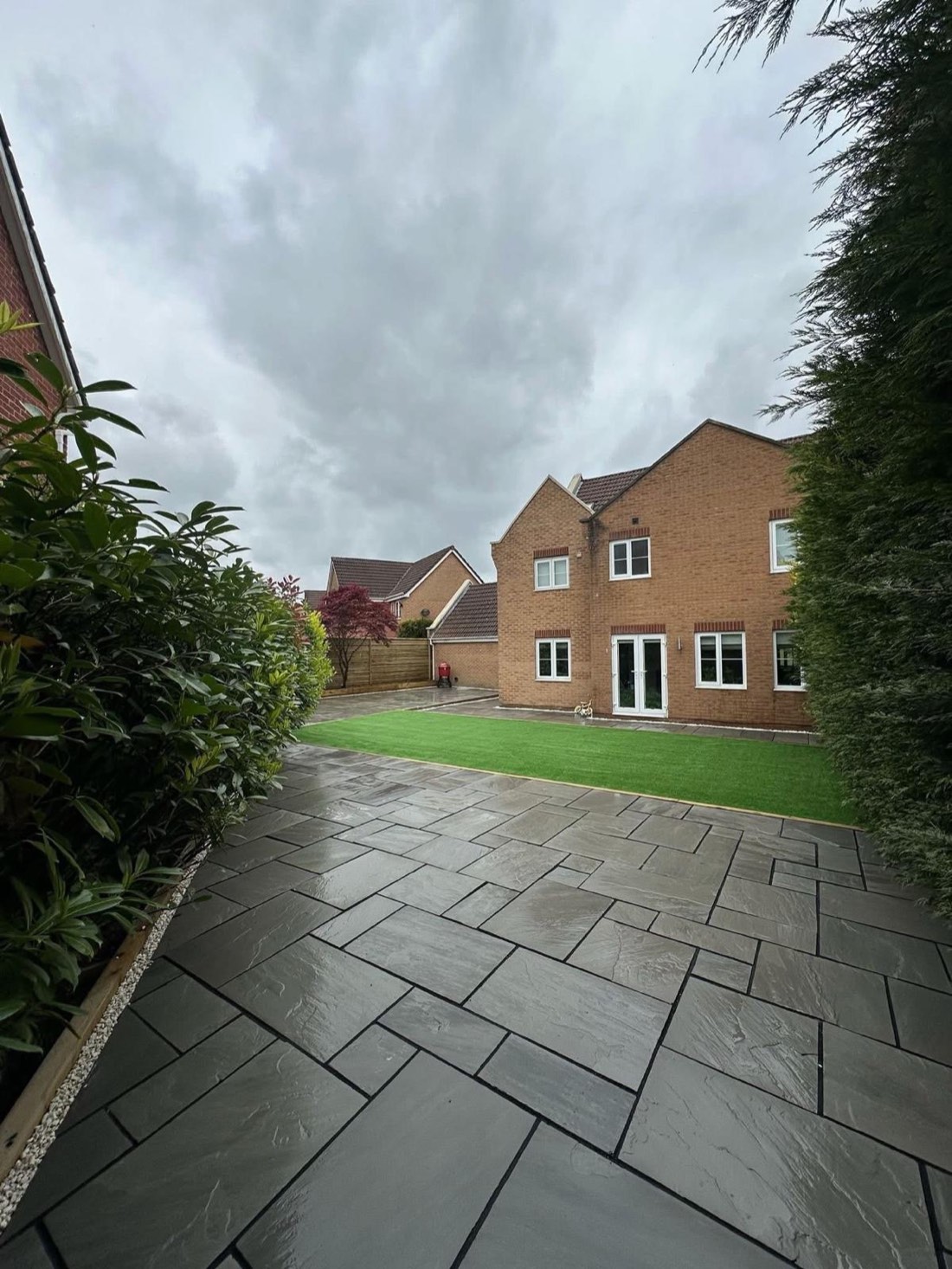 The same view of Dominic's garden after the rebuild — new paving and artificial grass