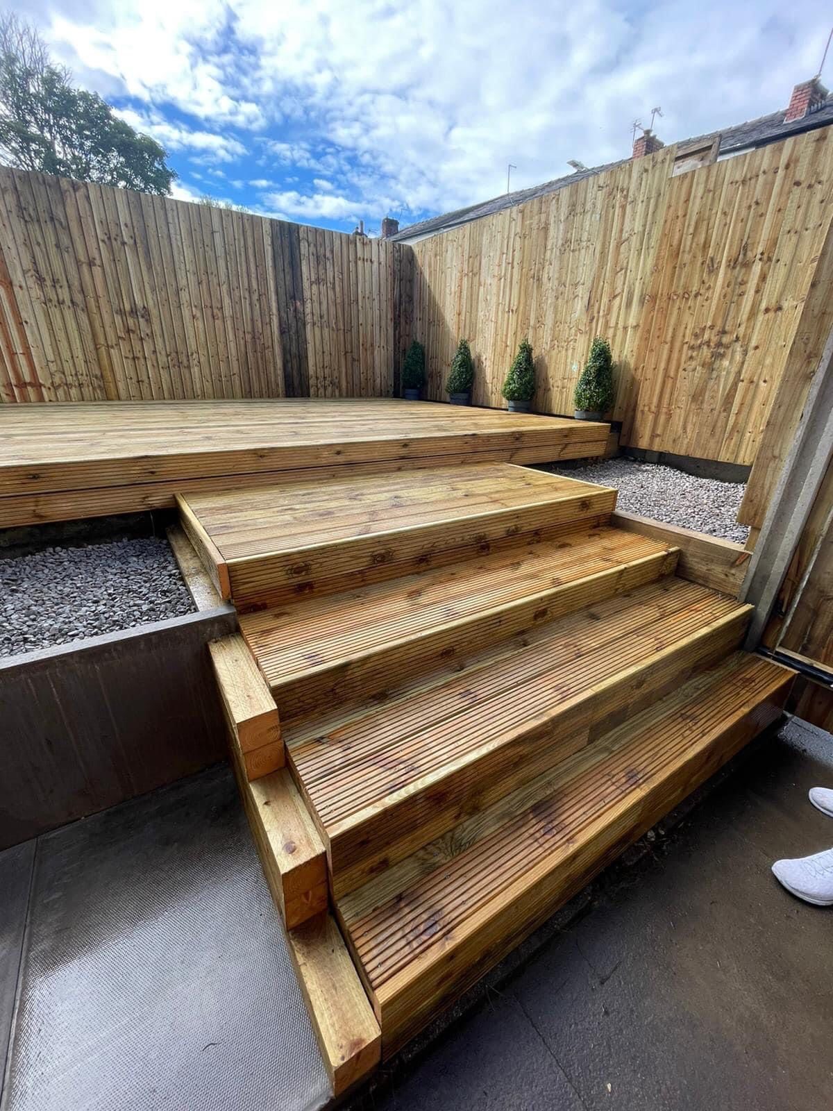 Multi-level decking with integrated steps in a sloped Bolton garden