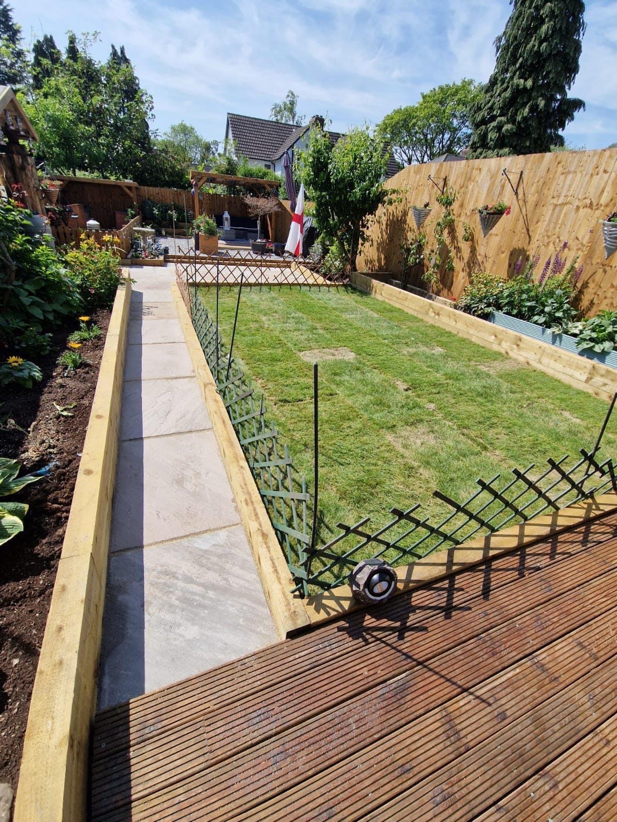 New timber decking, freshly laid lawn and sleeper-edged beds in a garden built by Northwest Elite Scaping