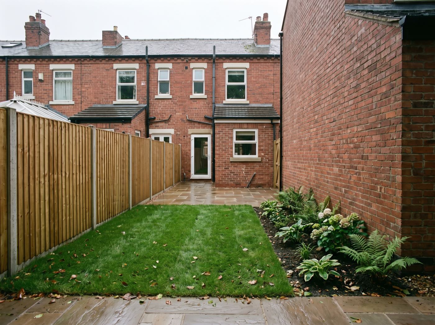 Finished back garden in Manchester after landscaping, with a new patio, lawn and fence (illustrative)