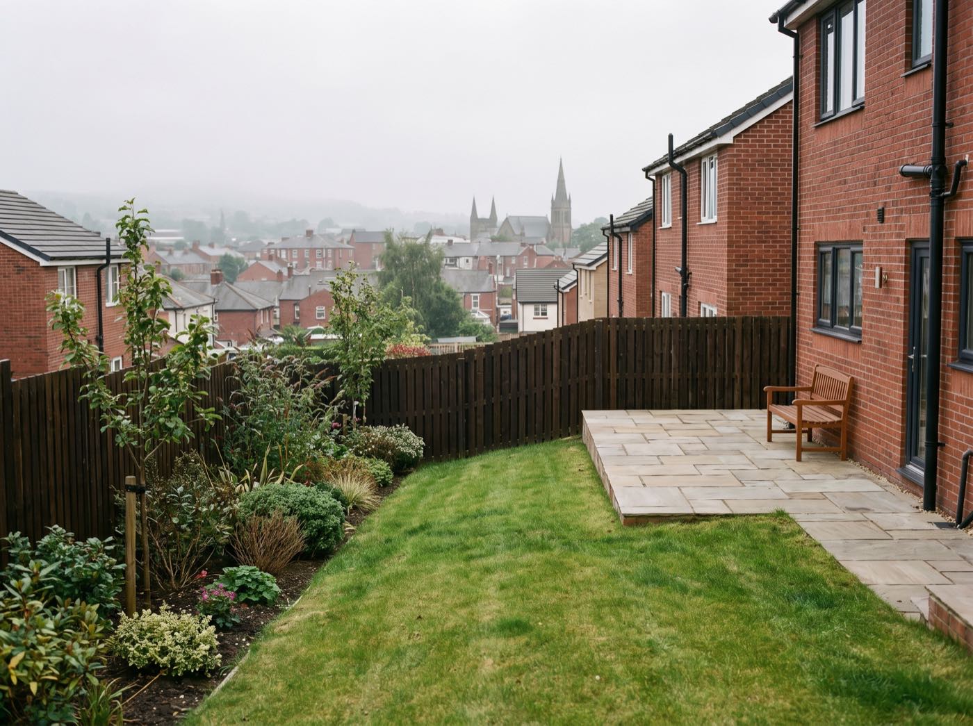 Finished back garden in Oldham after landscaping, with a new patio, lawn and fence (illustrative)