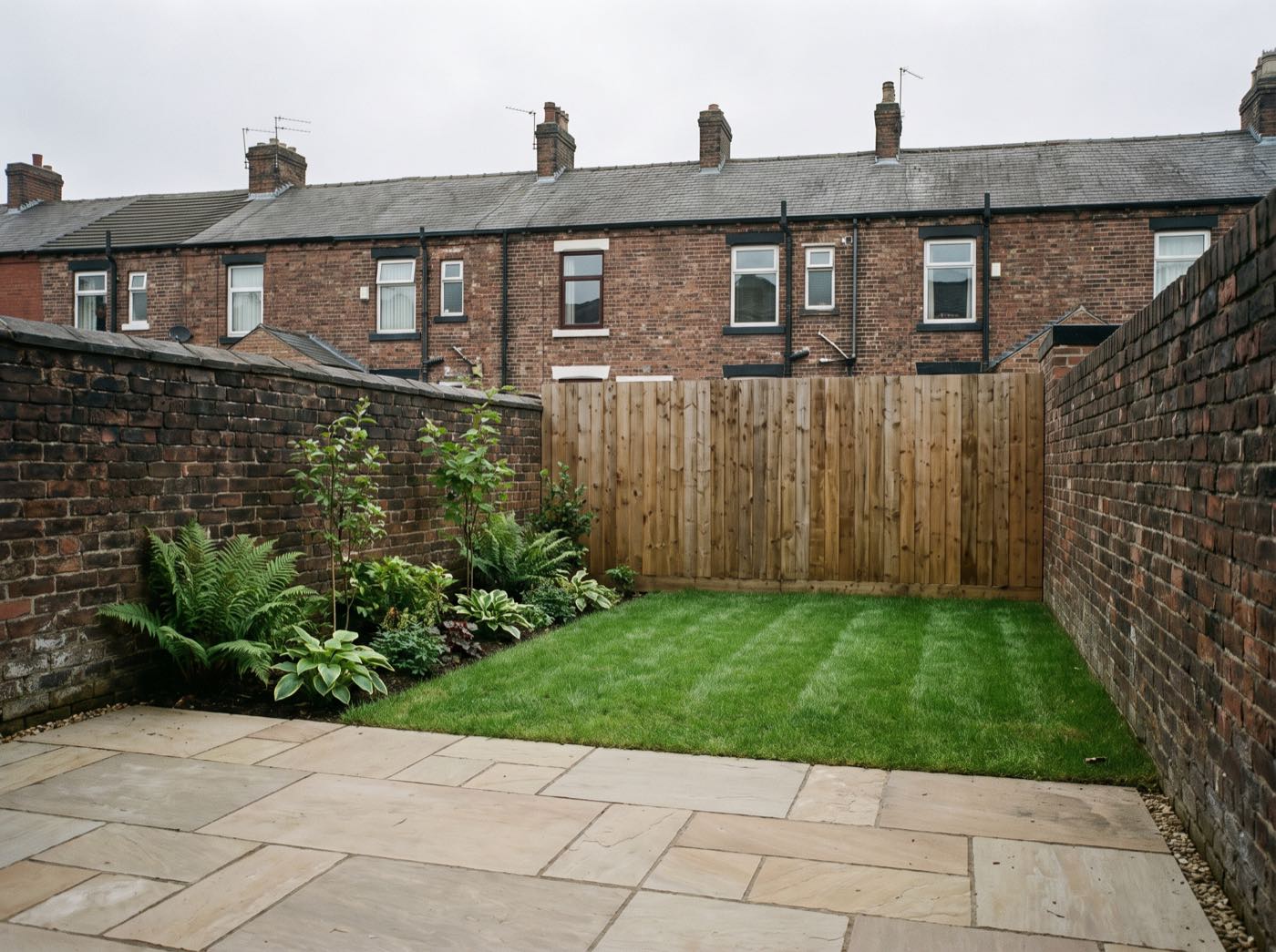 Finished back garden in Salford after landscaping, with a new patio, lawn and fence (illustrative)