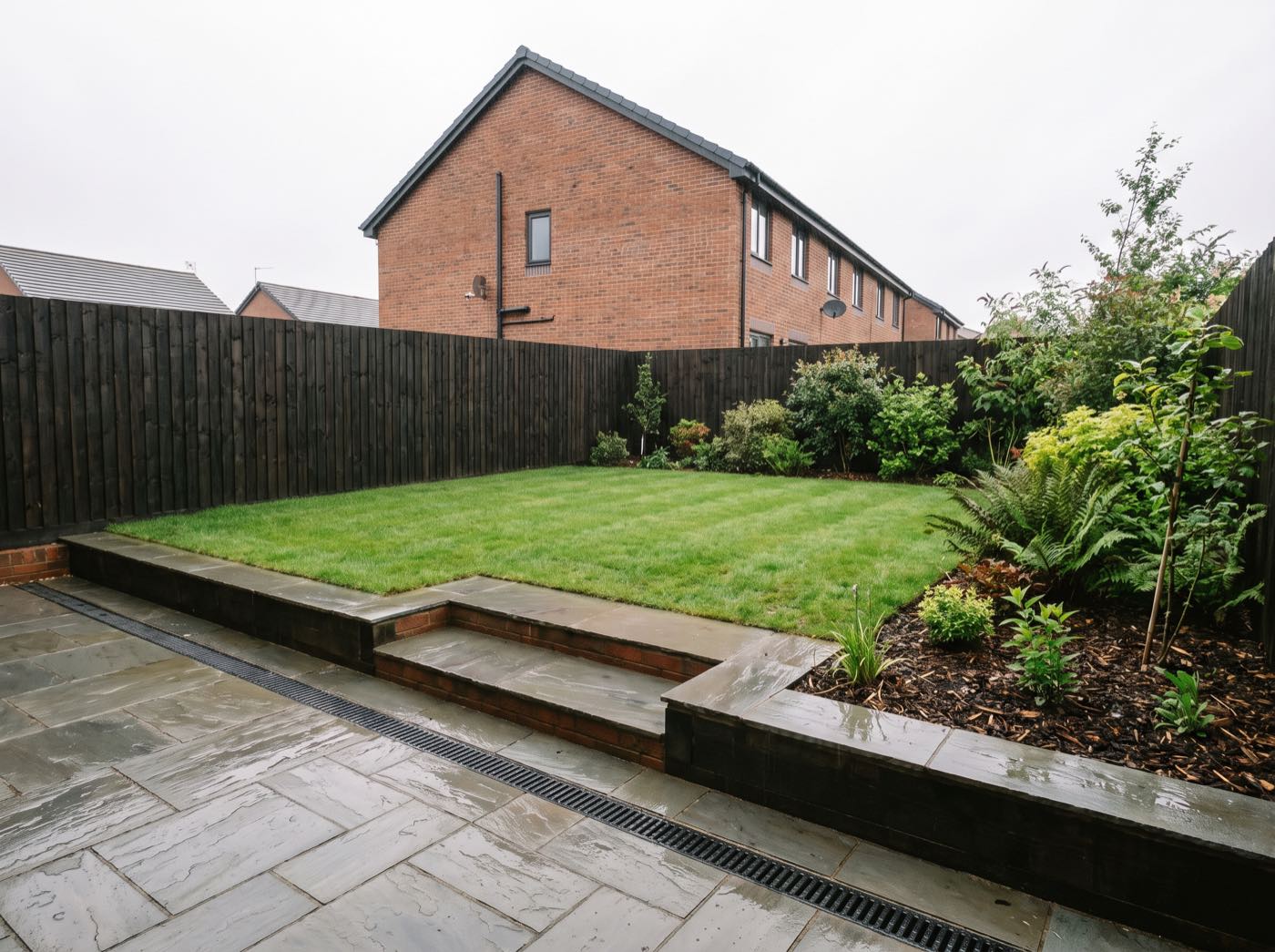 Finished back garden in Leigh after landscaping, with a new patio, lawn and fence (illustrative)