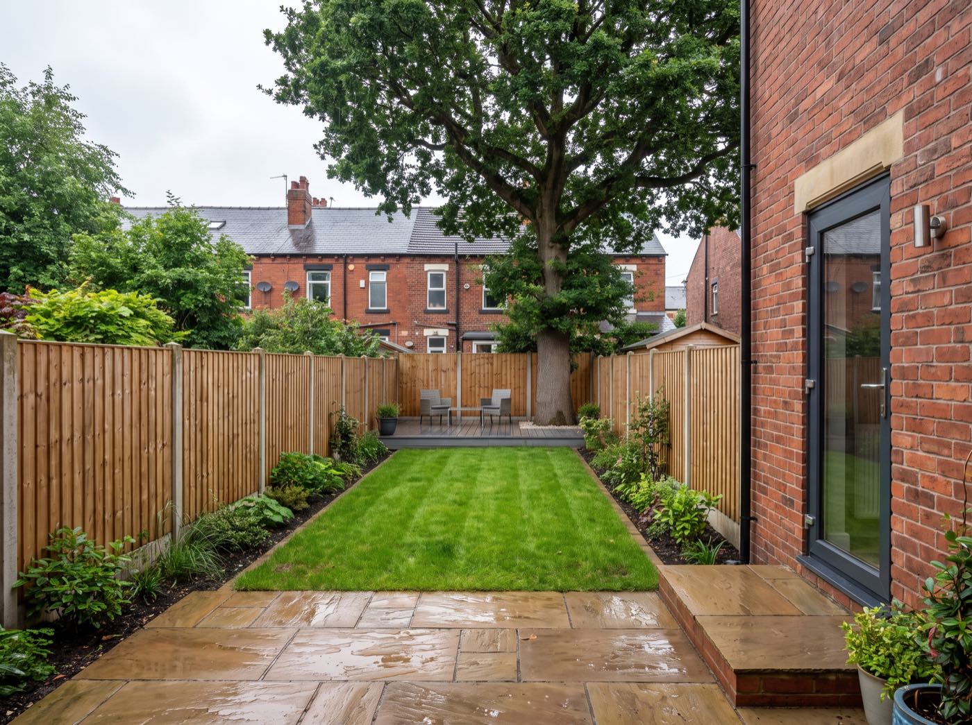 Long narrow terraced back garden in south Manchester after landscaping: sandstone patio, lawn and decking at the far end (illustrative)